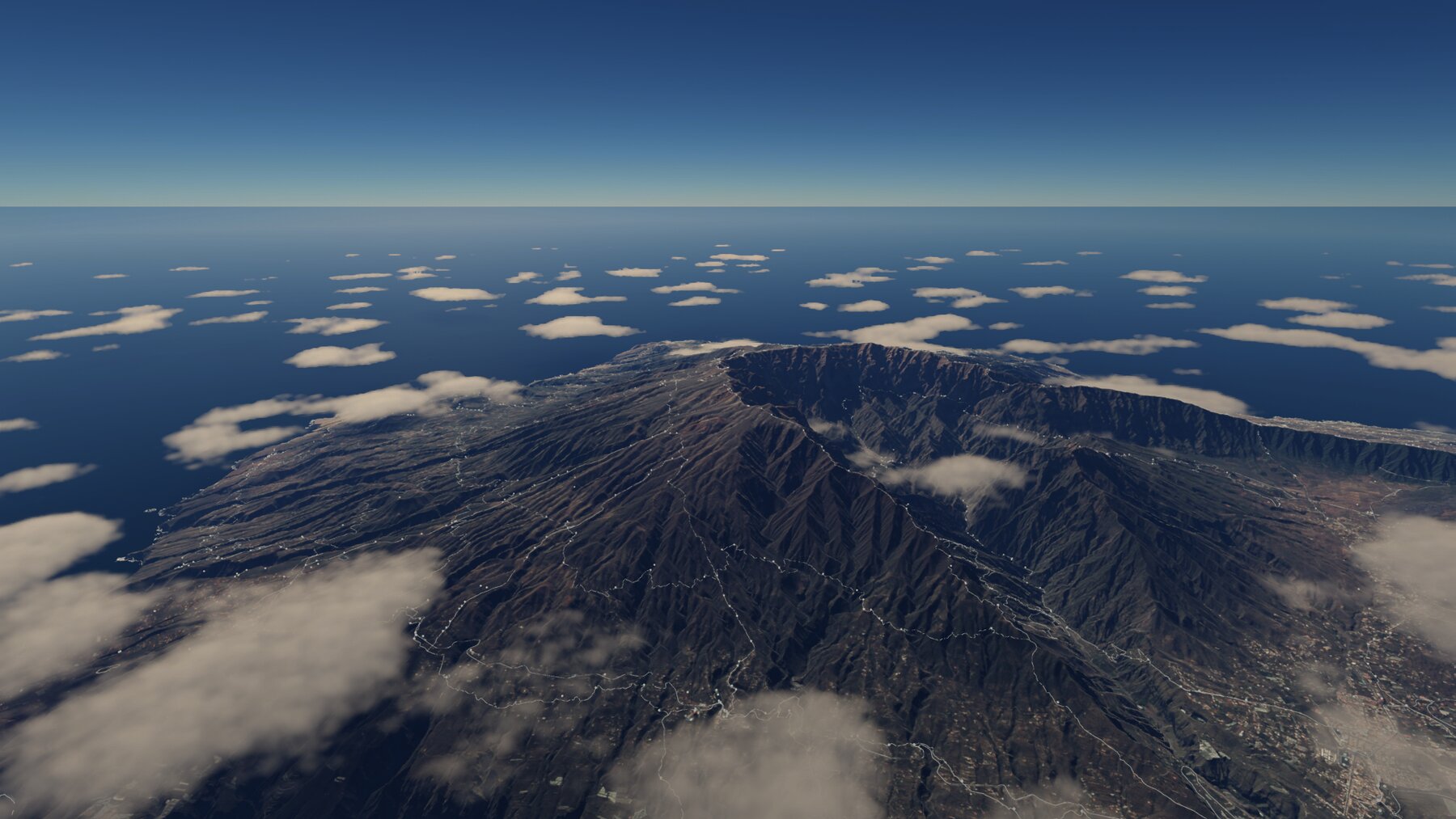La Caldera de Taburiente vista desde el aire, con la red de senderos marcada en blanco bajando por las laderas y cúmulos sueltos sobre el Atlántico.