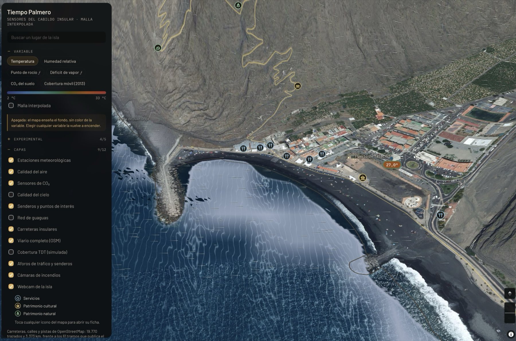 Puerto de Tazacorte visto desde arriba sobre ortofoto de alta resolución, con el mar simulado en movimiento frente a la playa y el panel de capas abierto a la izquierda mostrando estaciones, sensores de CO2, senderos, carreteras y webcam.
